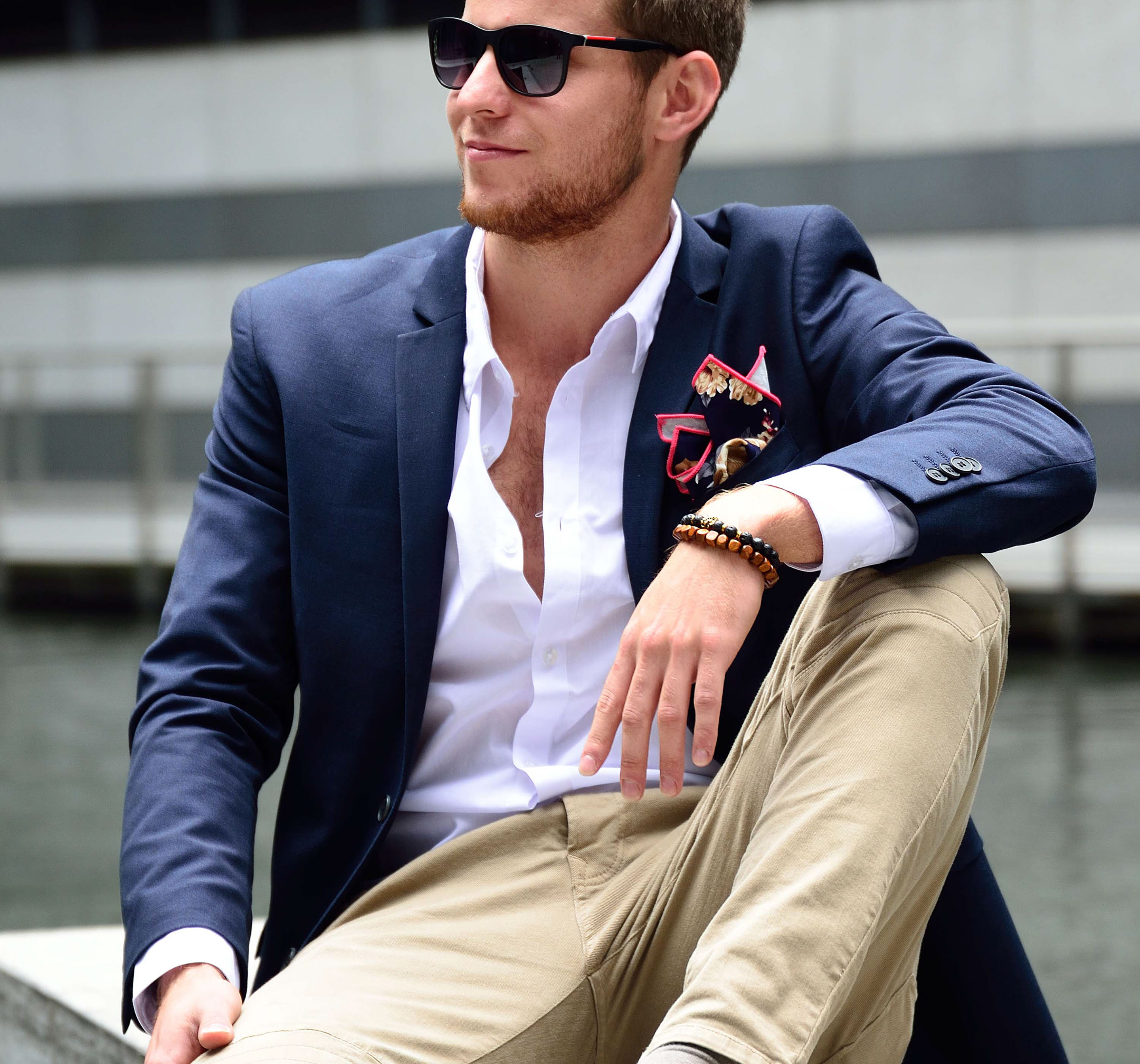 Four self-confident men wearing di Venisco pocket squares standing in front of a modern building.