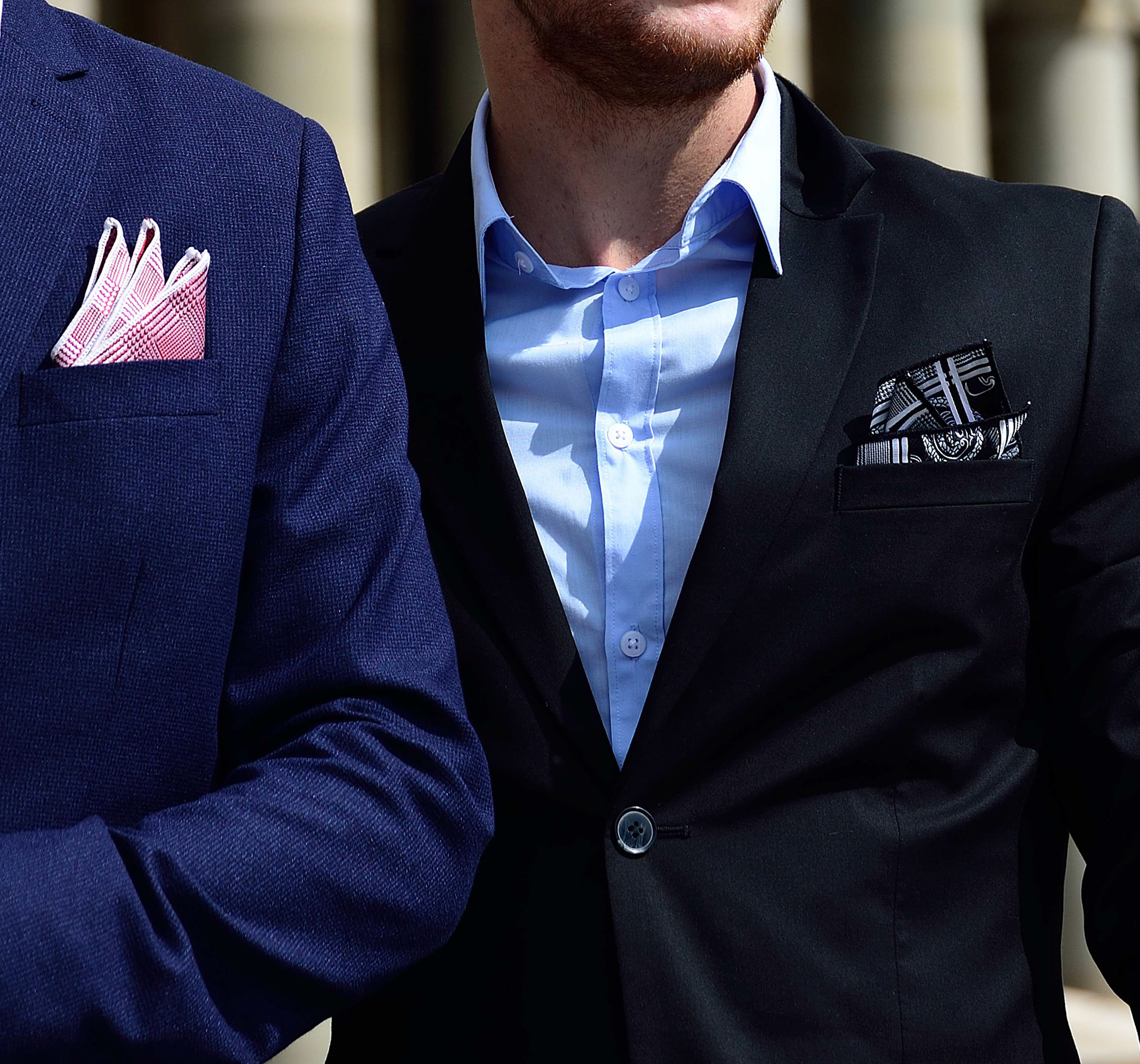 Four self-confident men wearing di Venisco pocket squares standing in front of a modern building.